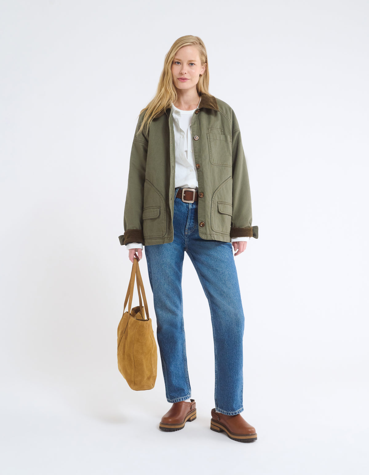 Homestead Barn Jacket with corduroy collar and sleeve trim on model styled with white button down shirt, straight denim jeans, muck clogs, statement brown leather belt and suede tote bag