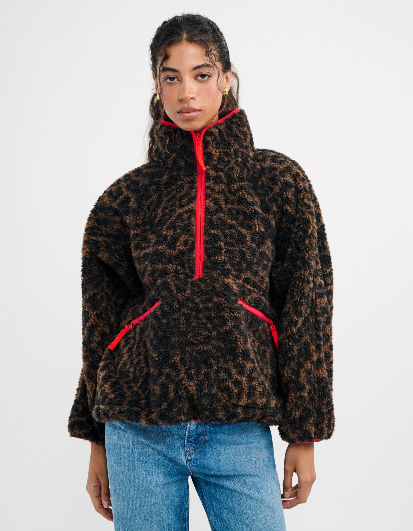 Cheetah Print- featuring a half-zip henley neckline outlined in red, oversized pockets positioned at the waist outlined in red, and raglan sleeves