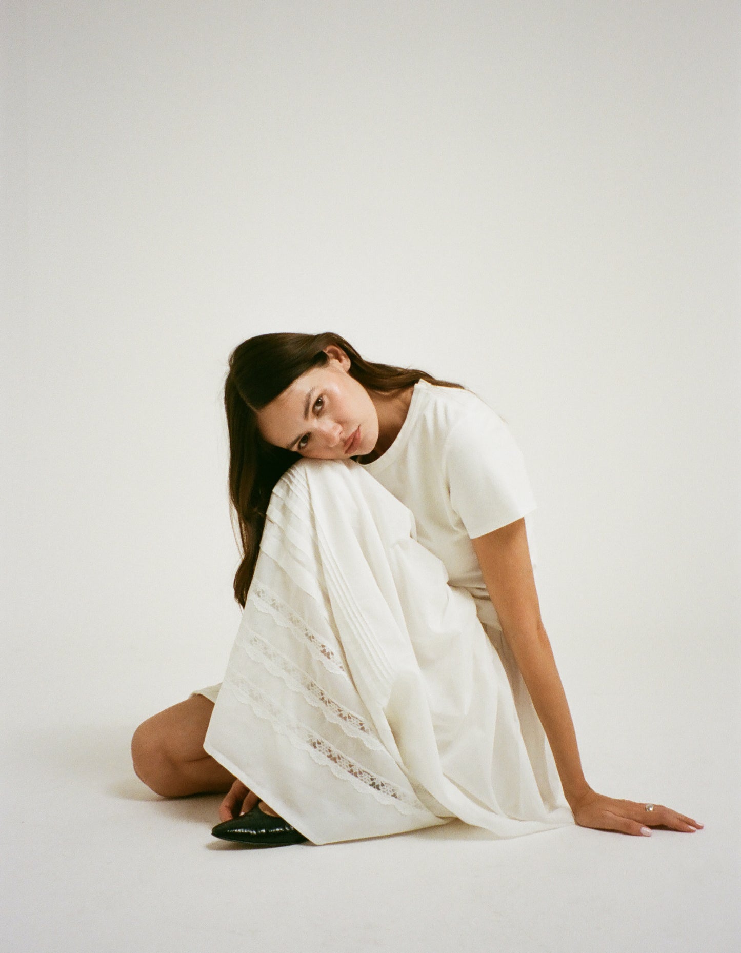 Model sitting down in white box tshirt and Maxi Skirt with lace detail on skirt.