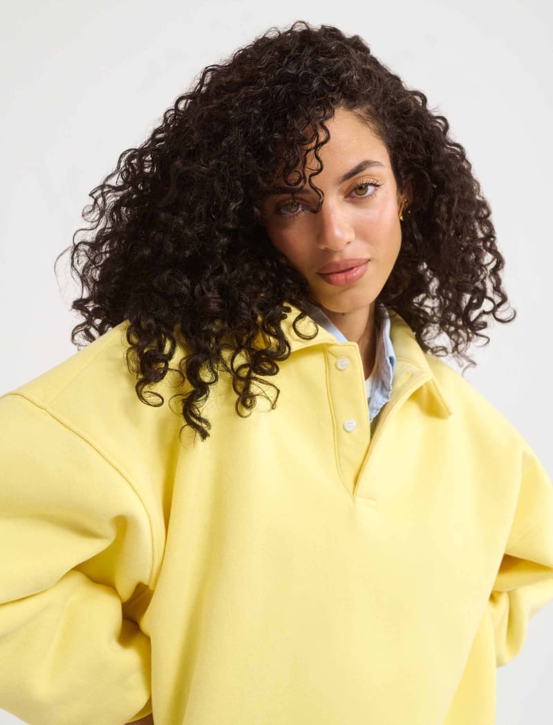 A model poses wearing Rumored 100% Cotton Airport Sweatshirt in Buttercream