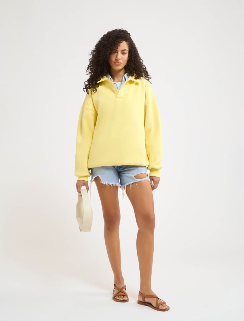 A model poses wearing Rumored 100% Cotton Airport Sweatshirt in Buttercream